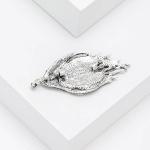 Silver feather brooch with abalone shell showing detailed back texture on white pedestal