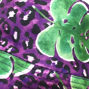 Detail of purple leopard print bucket hat with green leaf patterns and sturdy stitching