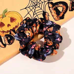 Detail of Halloween hair scrunchie with orange pumpkin and owl patterns on black fabric