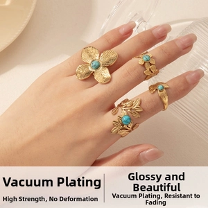Detail of four-piece gold flower leaf rings with turquoise stones on hand