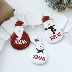 Three Christmas resin charms with Santa, snowman and deer figures on a white tray