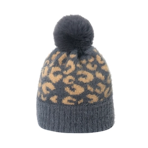 Détail du bonnet léopard en maille, texture fausse fourrure avec grand pompon gris doux