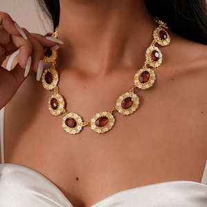 Close-up of vintage golden necklace with red oval gems and white flower details