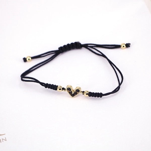 Close-up of heart-shaped charm bracelet with black pavé stones and woven cord