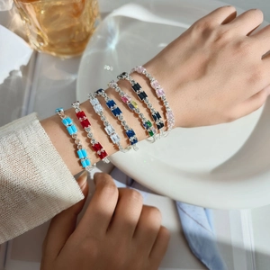 Close-up of elegant gold bracelets featuring vibrant multi-colored rectangular zirconia