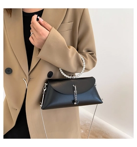 Detail of a black jelly handbag with rhinestone ring handle and silver chain strap