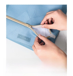 Detail of auto-lock khaki zipper on light blue mesh laundry bag for washing machines