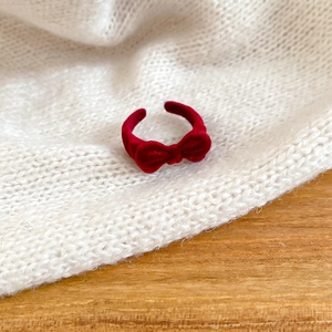 Macro detail of red velvet bow ring with adjustable band on white knit sweater