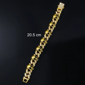 Macro detail of 20.5 cm gold-plated skull Cuban link bracelet with iced-out crystals