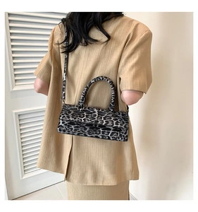 Close-up of leopard print crossbody bag worn by a model in a minimalist setting