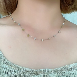 Detailed view of silver stainless steel chain with irregular yellow natural stones on neck