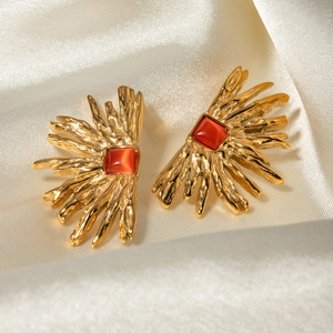 Close-up of red gemstone set in 18k gold irregular sunburst texture metal stud