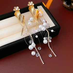 Detail of golden leaf earrings with white pearls and crystals in a black jewelry box