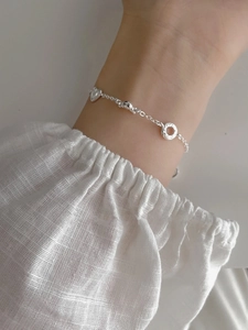 Detail of S925 sterling silver pretzel bracelet with heart charms on model wrist