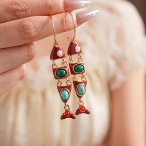 Détail de boucles d'oreilles poisson vintage en émail rouge avec pierres colorées
