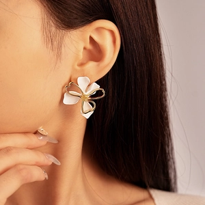 Detail of white and gold double-layered flower stud earring worn by a model