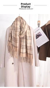 Detail of warm beige checkered scarf with tassels draped over a wool coat for autumn