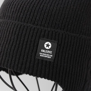Close-up of black ribbed knit beanie featuring a branded textile patch with white logo
