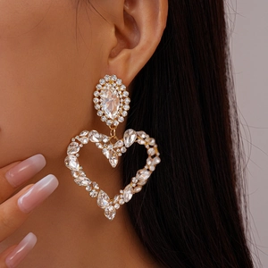 Close-up of sparkling heart-shaped oversized rhinestone earrings with gold plating