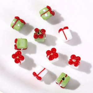 Close-up of green and white glass beads in Christmas gift box shape with red bows
