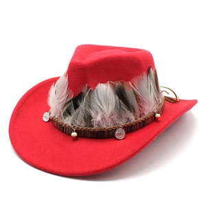 Detail of red wool cowboy hat with ethnic style feathers and metal charms