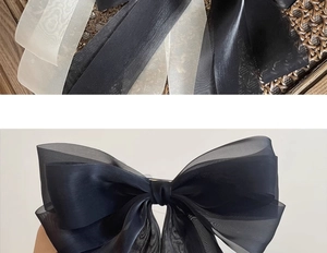 Detail of elegant black layered organza bow hairclip with translucent silk texture