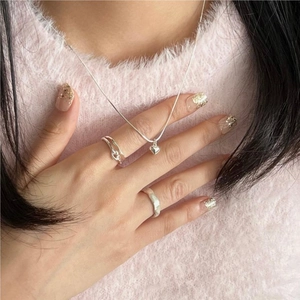 Detailed close-up of 925 sterling silver heart necklace and twisted stackable rings
