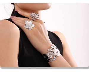 Detailed view of silver flower rings and wide cuff bracelet on a model's hand