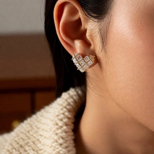 Detail of 18k gold heart earring with grid-set cubic zirconia on a female model