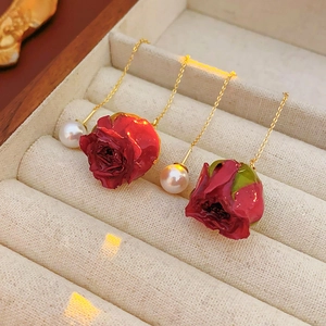 Vue détaillée de boucles d'oreilles roses rouges avec perles dans un écrin en velours