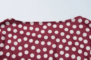 Close-up of crew neckline on a burgundy dress with white polka dot print details