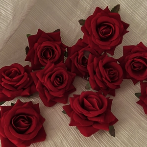 Detailed close-up of dark red velvet rose hair clip with realistic petals and green leaves