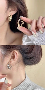 Détail de boucles d'oreilles irrégulières en métal poli de couleurs dorée et argentée