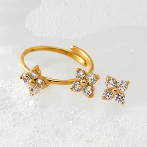 Golden stainless steel adjustable ring with clover design and zircon crystals on white foam
