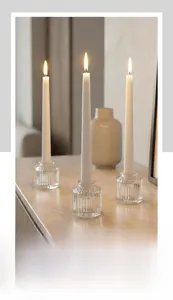 Dettaglio di tre portacandele in vetro a costine con eleganti candele bianche lunghe