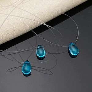 Teardrop-shaped blue glass pendant necklace on invisible fishing line minimalist style