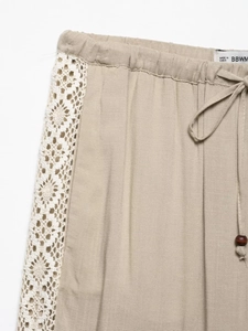 Detail of apricot wide leg trousers with elastic waist, drawstring and lace side trim