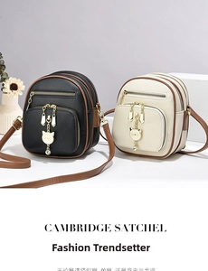 Macro detail of multi-layer zippers and cat-shaped metal charm on litchi grain leather bag