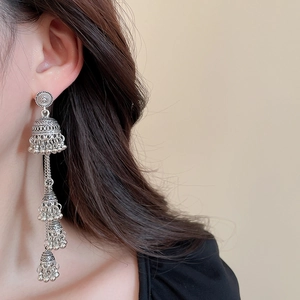 Detail of silver layered bell tassel earrings worn by model in a boho vintage style