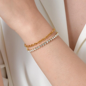 Detail of stacked gold rope chain and silver tennis bracelet with clear zircon stones