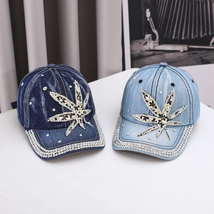 Detailed close-up of rhinestone leaf patterns on washed denim baseball cap with crystal brim