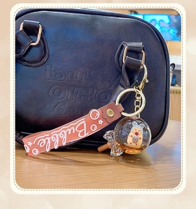 Detail of pink silicone strap and bubble tea keychain charm on a black handbag