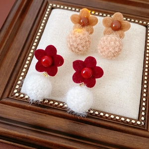 Detail of flocking flower and pompom earrings on a vintage display for winter fashion