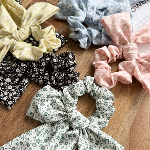 Floral print bow hair scrunchies in multiple colors on a natural wooden background