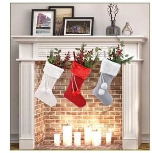 Chaussettes de Noël tricotées rouges, blanches et grises suspendues à une cheminée festive