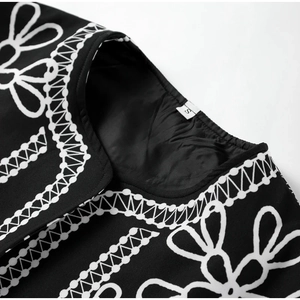 Detail of neckline with embroidery and size S label on black contrast printed top