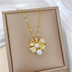Macro view of gold bow necklace with rhinestones and pearl on premium jewelry box
