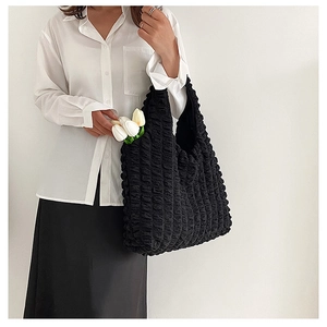 Detail of black puff textured tote bag styled with a white shirt and fresh tulips