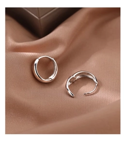 Macro shot of silver U-shaped hoop earrings with S925 hallmark on silk fabric