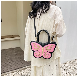 Detail of butterfly-shaped PU leather bag in pink and black with golden glitter accents